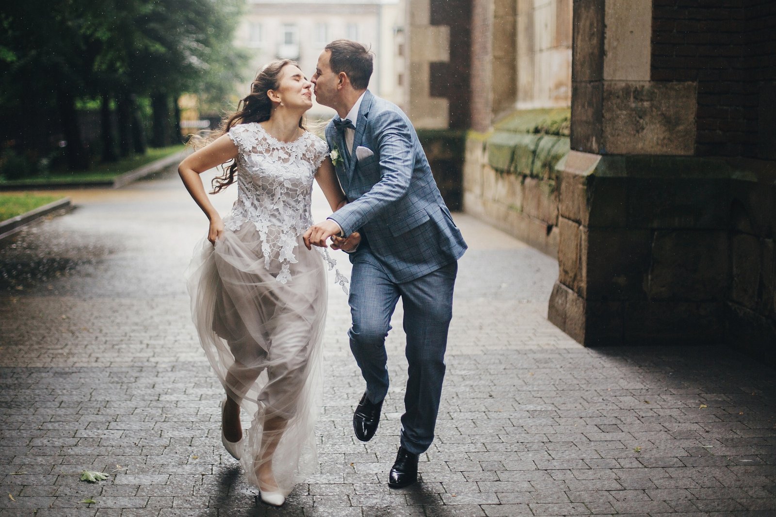 Beautiful happy wedding couple smiling and kissing in rain in european city. Provence wedding