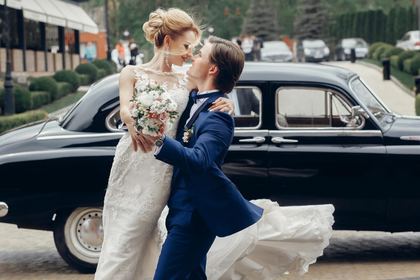 Luxury wedding couple dancing at old car in light