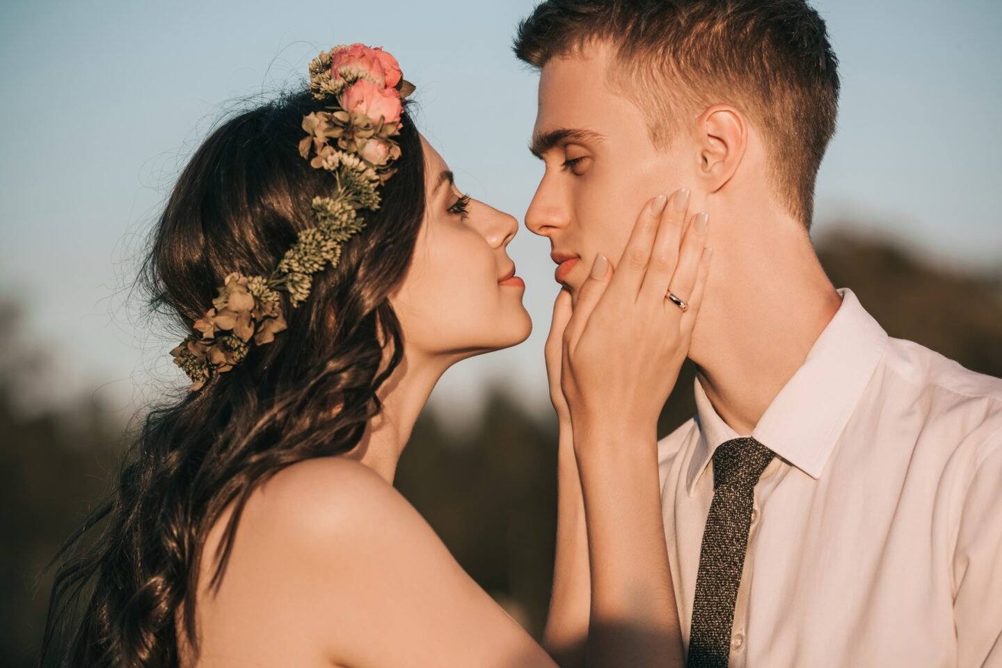 side view of beautiful happy young wedding couple able to kiss in park