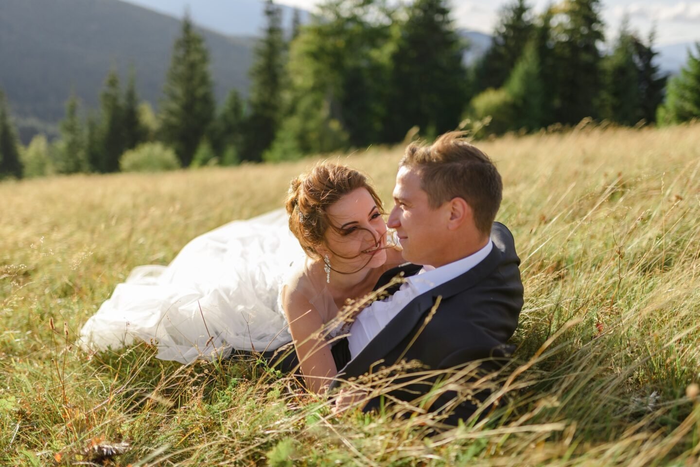 Wedding photography in the mountains. Newlyweds are lying in the grass.